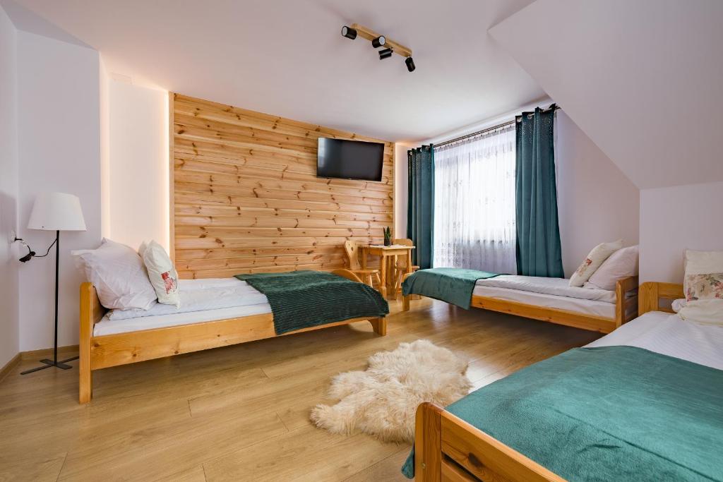 a bedroom with two beds and a television in it at Apartament u Wróbla in Leśnica