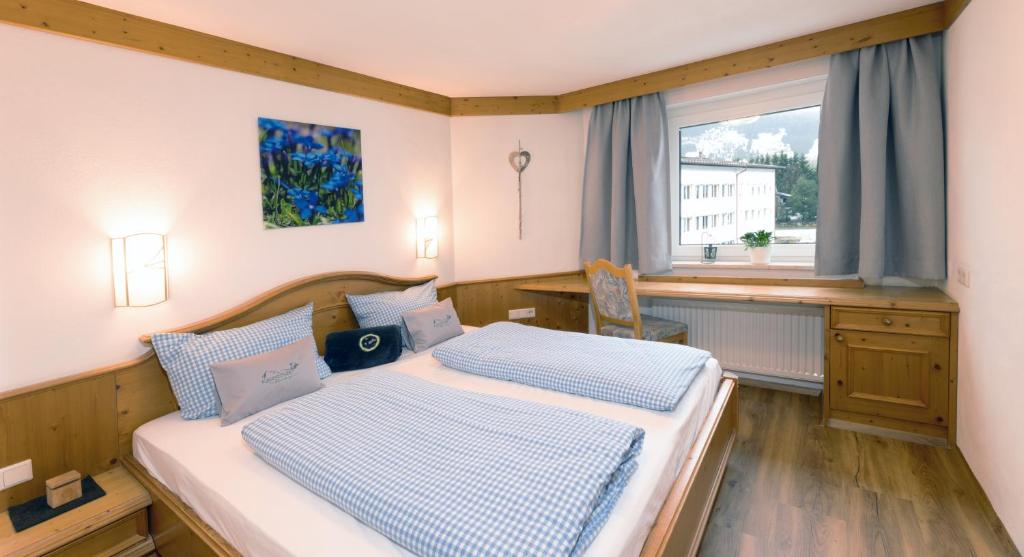 een slaapkamer met 2 bedden en een raam bij Käserstube Ferienwohnungen in Tannheim