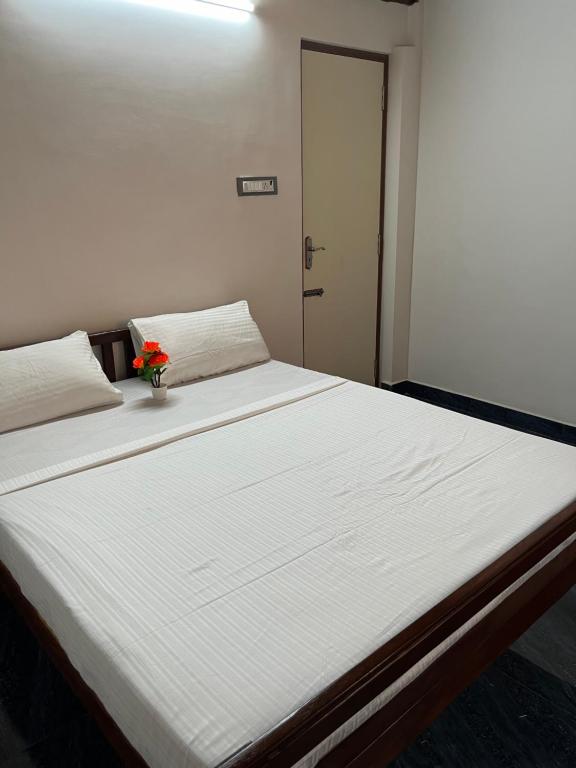 uma grande cama branca com um vaso de flores em Serenity Bay Home Stay em Pondicherry