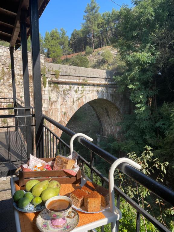 a table with food on a balcony with a bridge at Τα πέτρινα γεφύρια in Dhimitsana