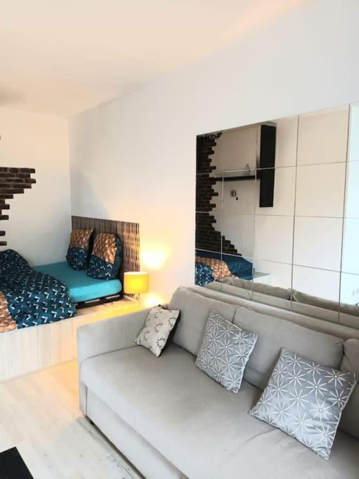 ein Wohnzimmer mit einem Sofa und einem Spiegel in der Unterkunft Bel Appart calme proche CDG in Gonesse