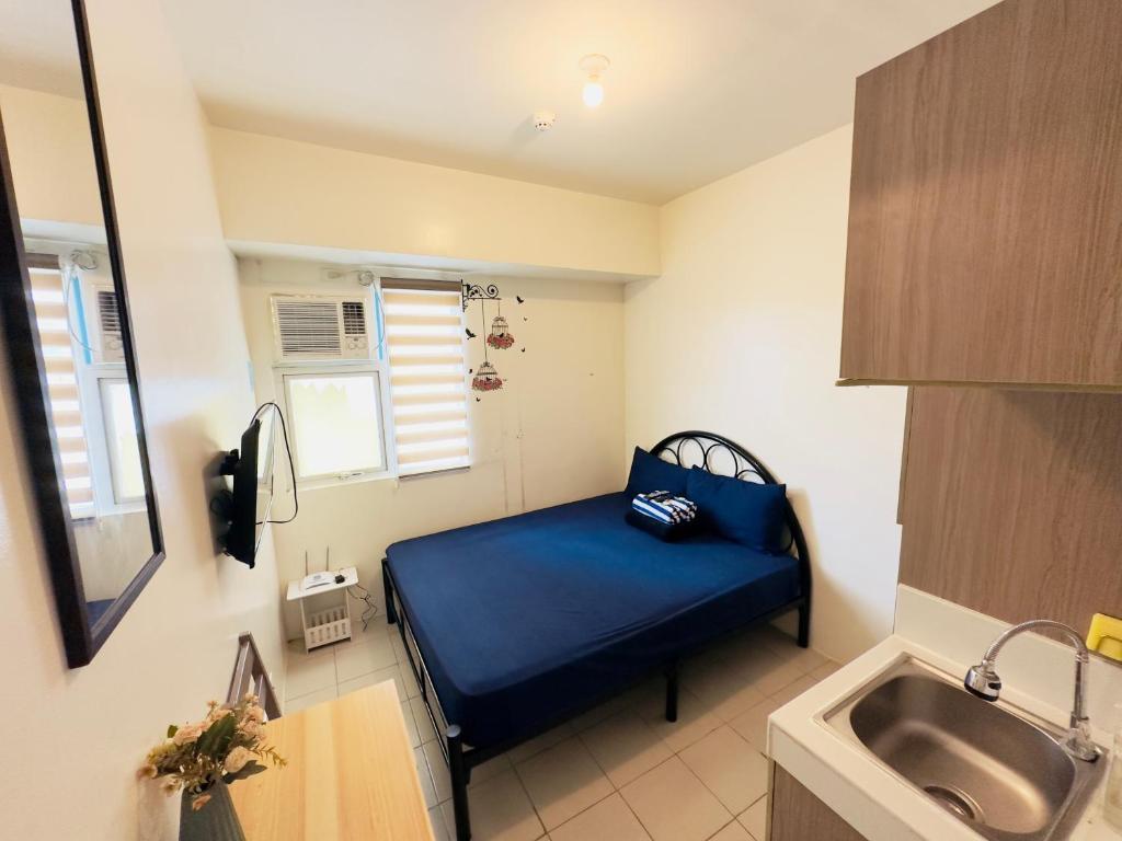 Habitación pequeña con cama azul y lavabo. en Hassle Free Check In and Out With Unli WiFi Netflix en Manila