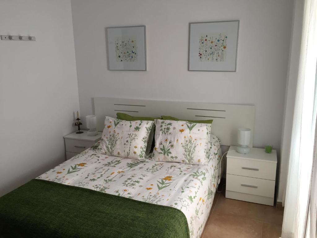 a bedroom with a bed with a green blanket and pillows at San Juan Apartamento in Jerez de la Frontera