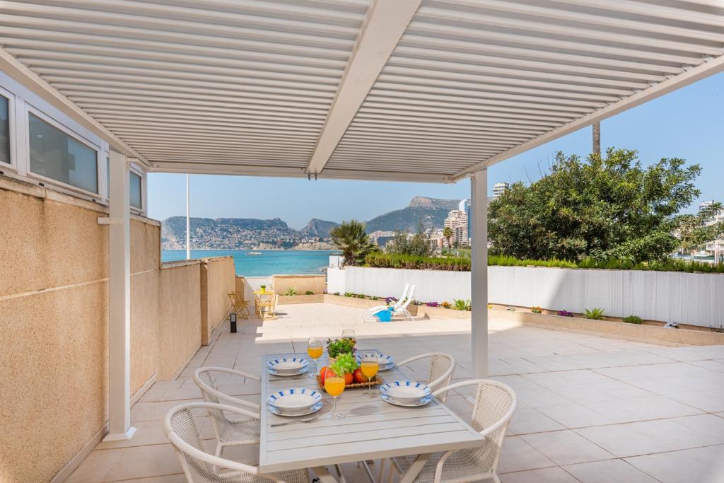 a patio with a table and chairs with a view of the ocean at Apartamento Casita Blanca - PlusHolidays in Calpe