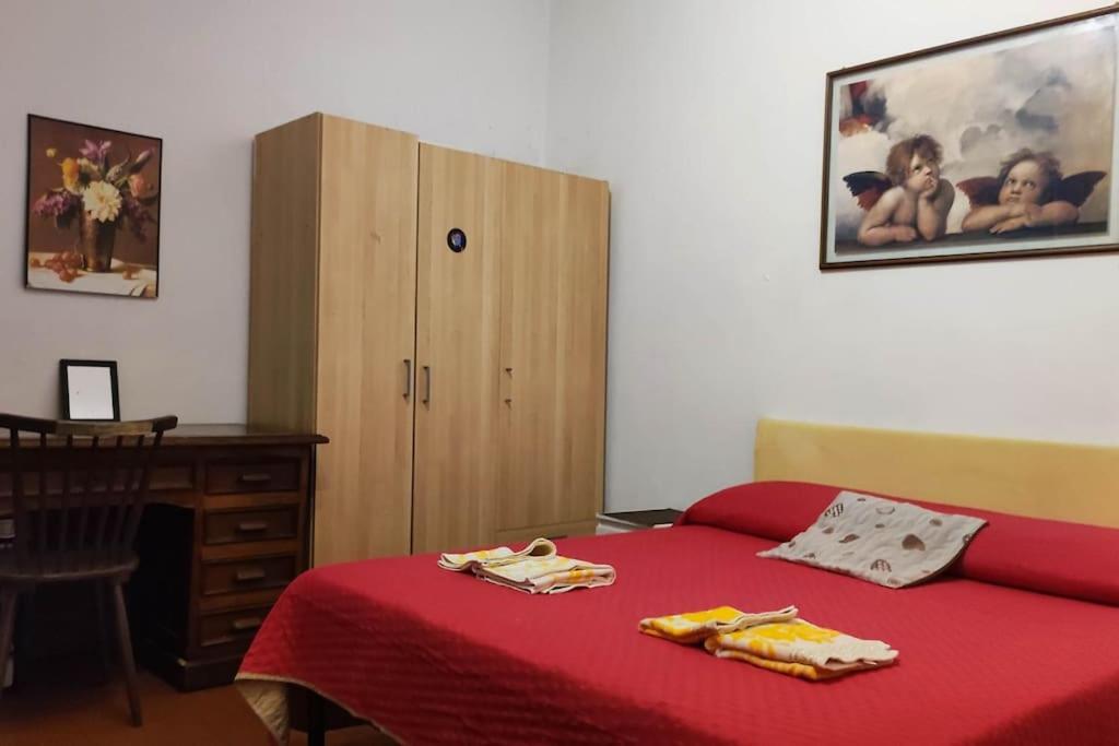 a bedroom with a red bed and a wooden cabinet at Casa nel cuore di Firenze. in Florence