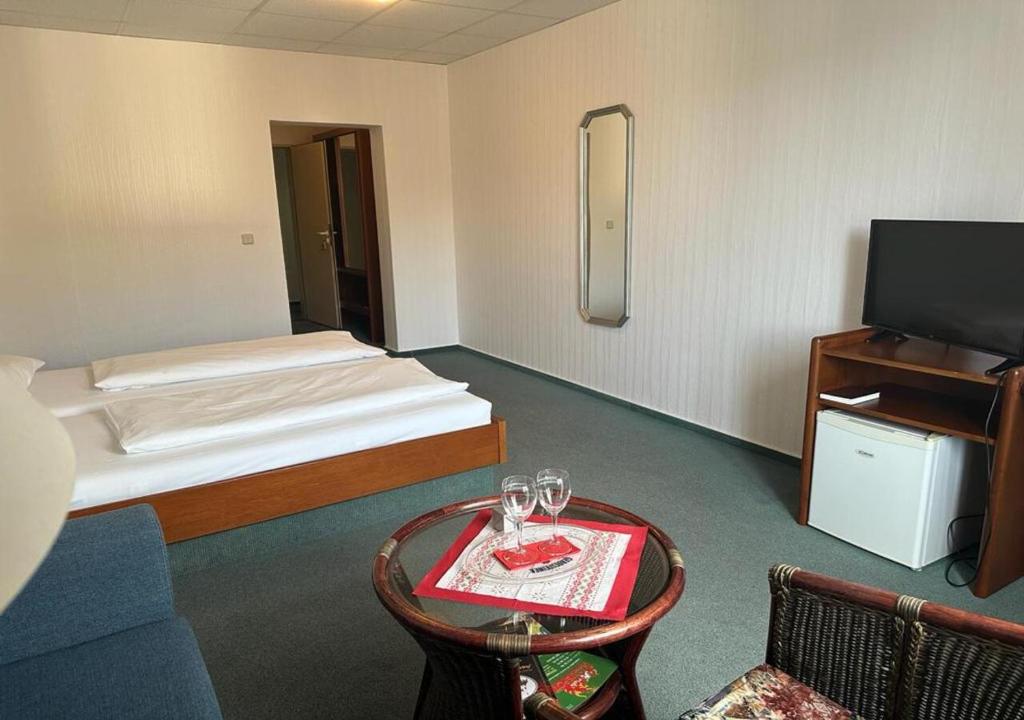 a room with a bed and a table with glasses on it at Mansfelder Hof in Lutherstadt Eisleben