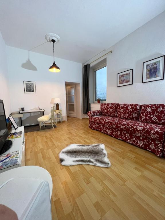 ein Wohnzimmer mit einem roten Sofa auf einem Holzboden in der Unterkunft Casa Estrella in Duisburg