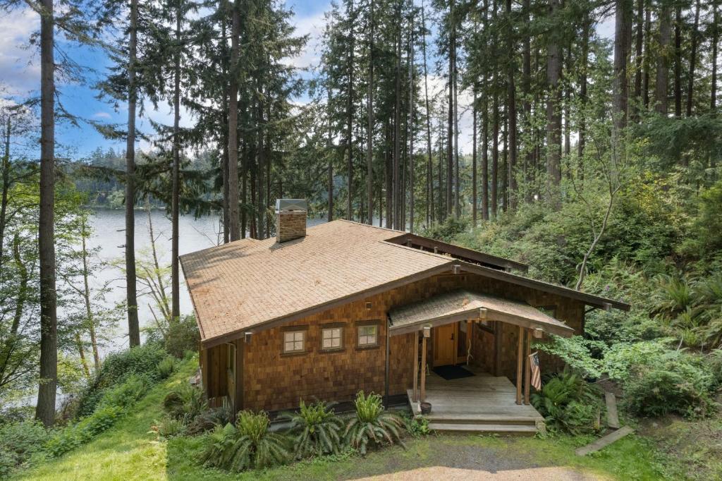a log cabin in the woods with a lake at Goss Lake Chalet by AvantStay Lakefront w Dock in Langley