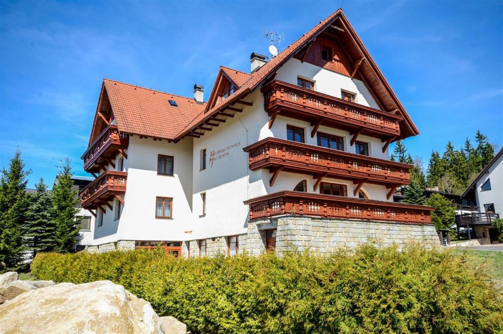 un grand bâtiment blanc avec un toit rouge dans l'établissement Harrachovská Hacienda, à Harrachov