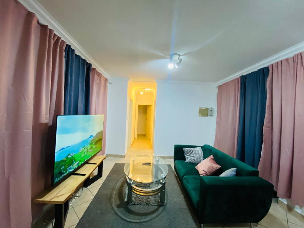 a living room with a couch and a flat screen tv at The crib in Roodepoort