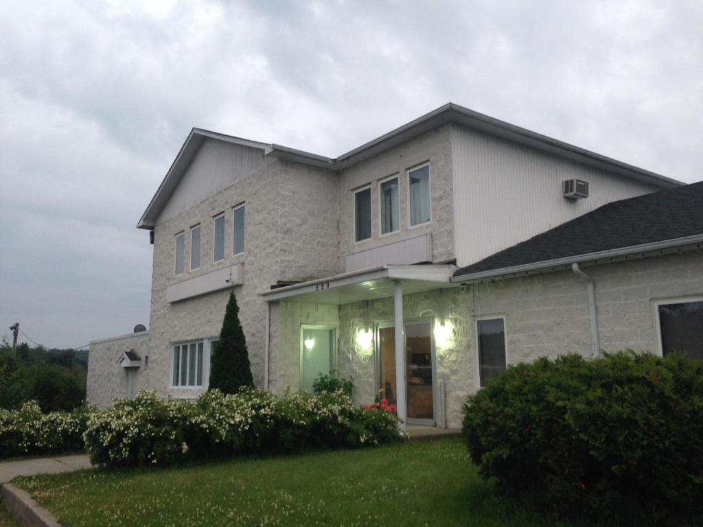 een groot wit huis met een groene tuin bij Motel Econonuit in Sherbrooke