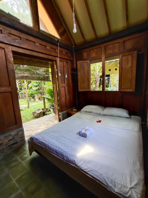 a bedroom with a bed in a room with windows at Mettaloka Guesthouse in Magelang