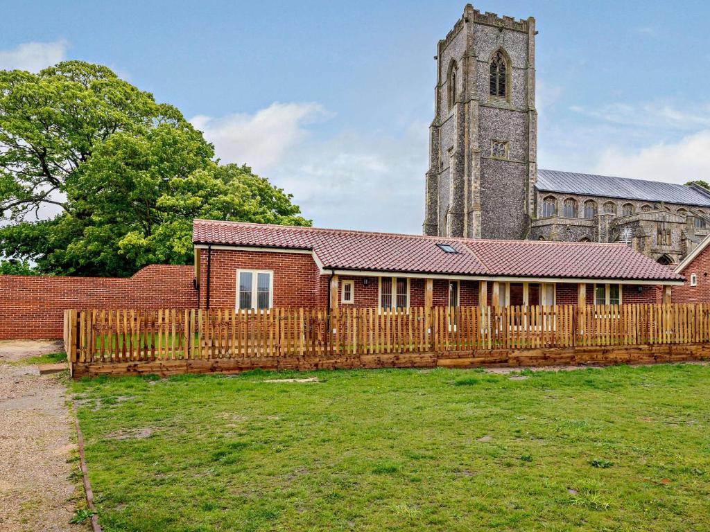a building with a wooden fence in front of a church at 3 Bed in Wroxham 83034 in Worstead
