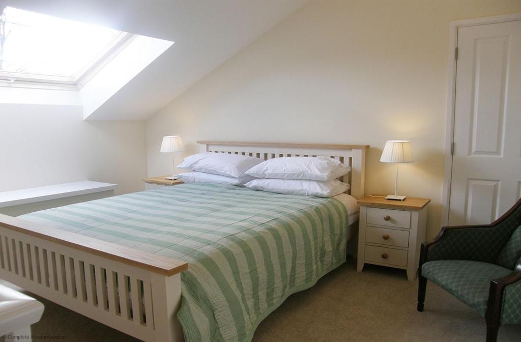 ein Schlafzimmer mit einem Bett, einem Fenster und einem Stuhl in der Unterkunft Goldridge in Alton