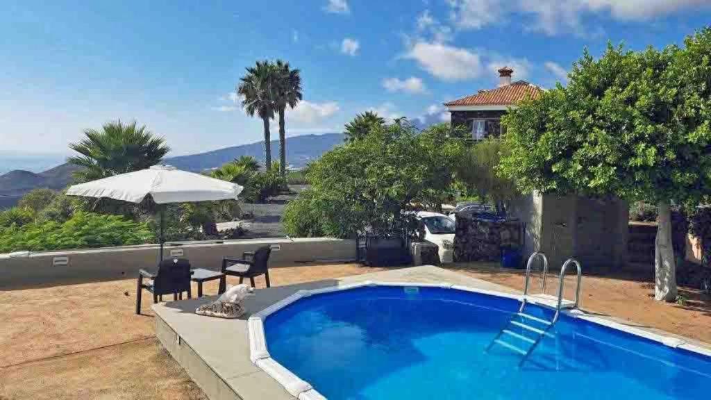 a pool with a table and chairs and a house at Appartement Caldera in Los Llanos de Aridane