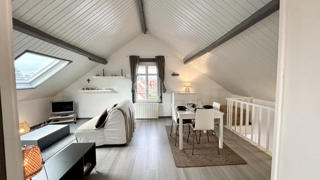 Cette chambre mansardée comprend un canapé et une table. dans l'établissement Les Tilleuls, au Crotoy