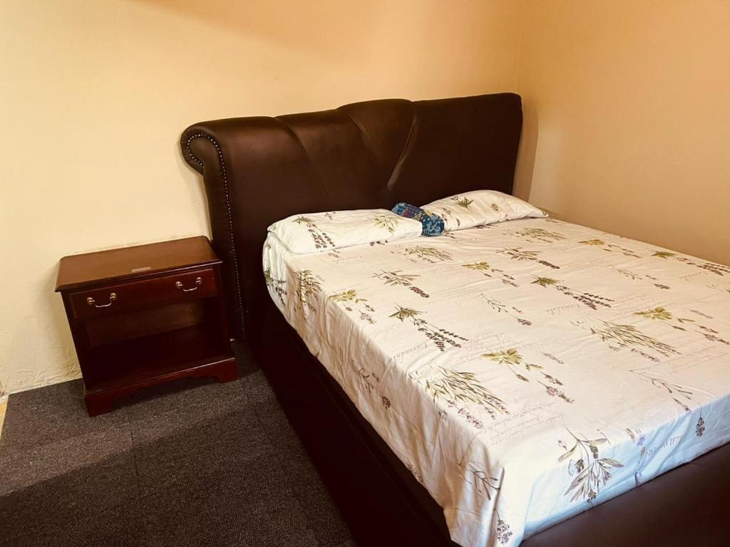 a bed with a leather headboard and a night stand at Mphatlalatsane BnB in Maseru