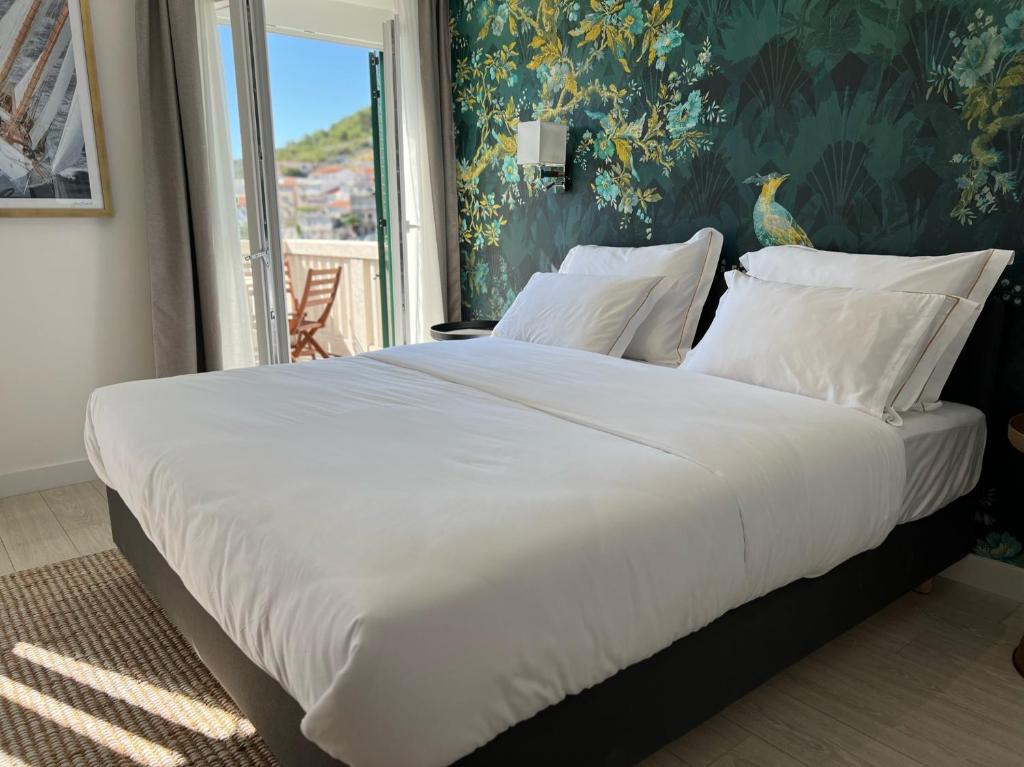 uma cama grande com lençóis brancos e almofadas num quarto em Adriana Zaton em Zaton