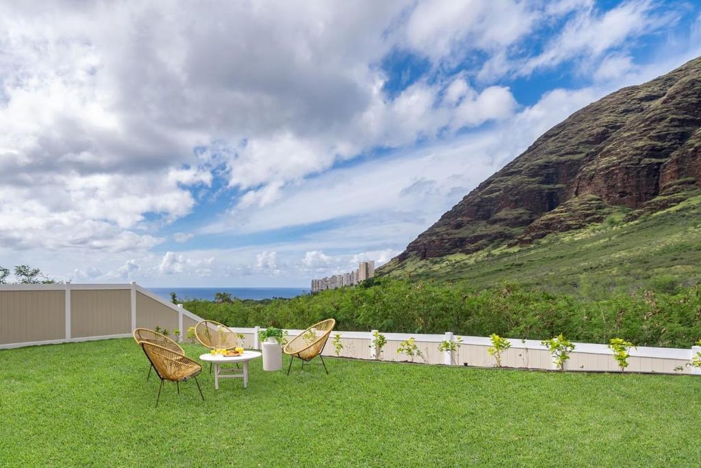 a patio with chairs and a table on the grass at Alaula by AvantStay Gated Security Home w Valley Ocean Views in Waianae