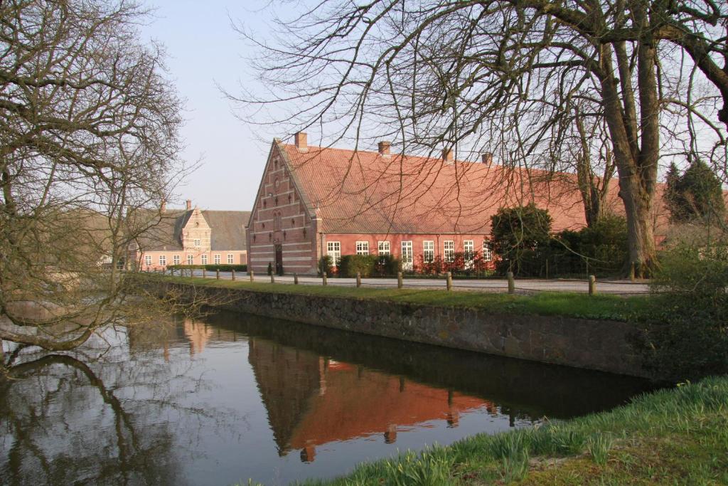 ein Gebäude neben einem Fluss mit einem Haus in der Unterkunft Vemmetofte Præstegård in Faxe