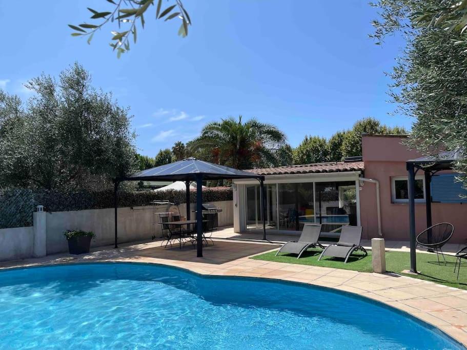 une piscine avec un parasol et des chaises à côté d'une maison dans l'établissement Villa climatisée piscine 3 chambres mer à 800m, à Antibes
