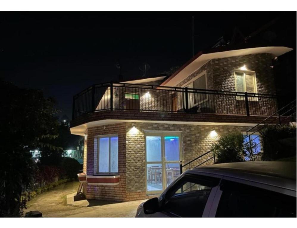 Una casa de ladrillo con un balcón encima por la noche en Kings Cottage, Bhimtal, en Bhimtal