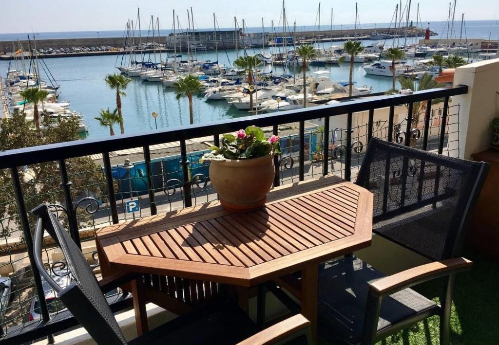 une table en bois avec une plante en pot sur un balcon avec un port dans l'établissement Vistas al Puerto, à La Vila Joiosa