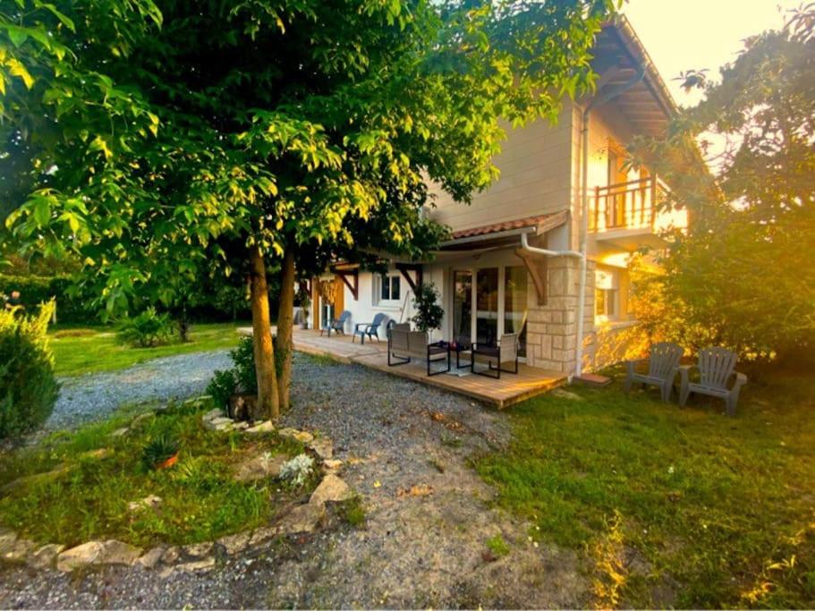 une maison avec une véranda et un arbre dans la cour dans l'établissement La Maison du Courant 3*, à Mimizan