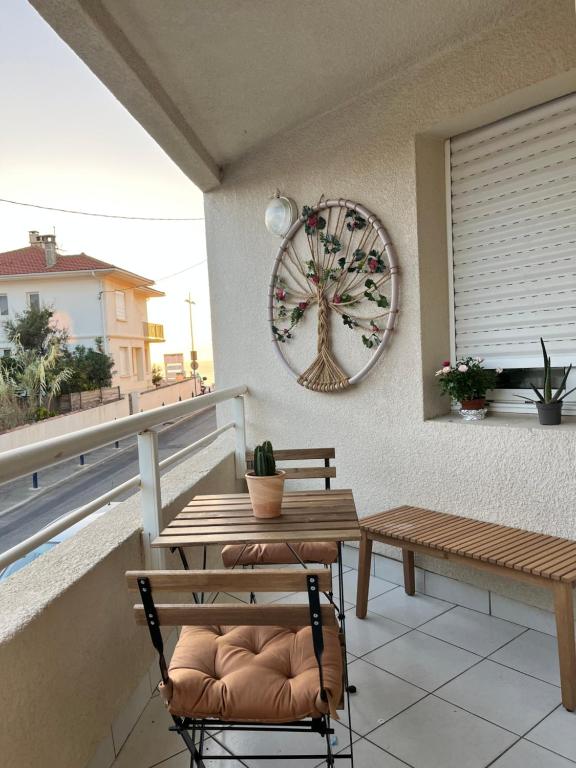 een houten tafel en bank op een balkon met een klok bij Appartement vue océan in Capbreton