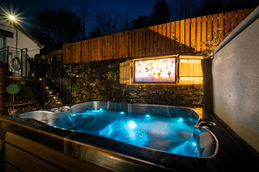 un jacuzzi en el patio trasero por la noche en Stunning cottage Grade 2 listed with parking and Hot Tub, en Bowness-on-Windermere