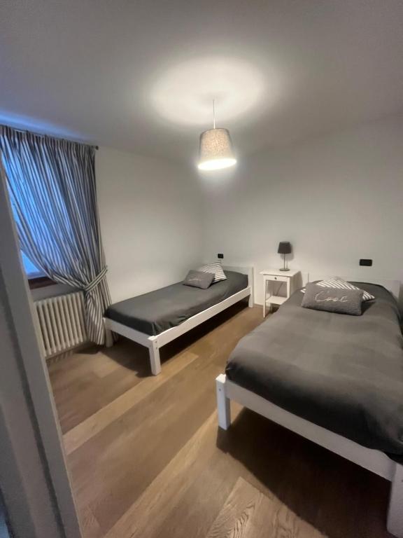 1 dormitorio con 2 camas y ventana en Casa Dani, en Baselga di Pinè