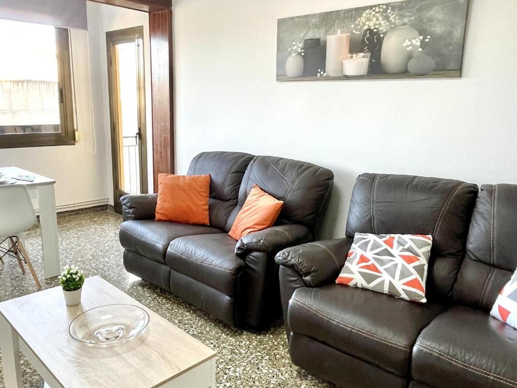 a living room with a leather couch and a table at APARTBEACH EL CARRILET CENTRICO y LUMINOSO in Reus