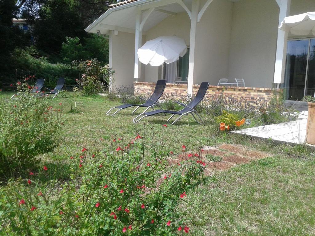 two chairs and an umbrella in the yard of a house at Chambres "Blanches" , bâtiment secondaire hotel la Caravelle, vue jardin in Biscarrosse-Plage