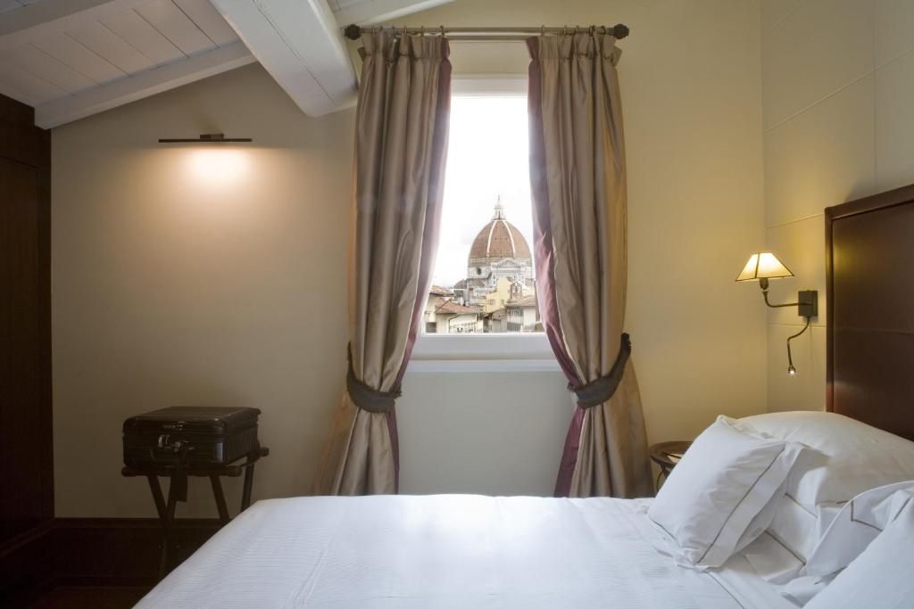 a bedroom with a white bed and a window at Hotel L'Orologio - WTB Hotels in Florence