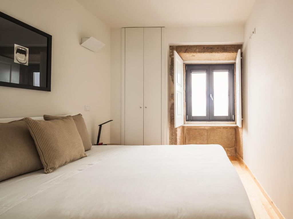 Schlafzimmer mit einem großen weißen Bett und einem Fenster in der Unterkunft InSitu Trindade by Guestify in Porto