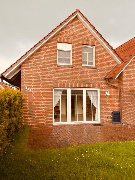 a brick house with large windows in a yard at Ferienhaus Dirka in Norddeich