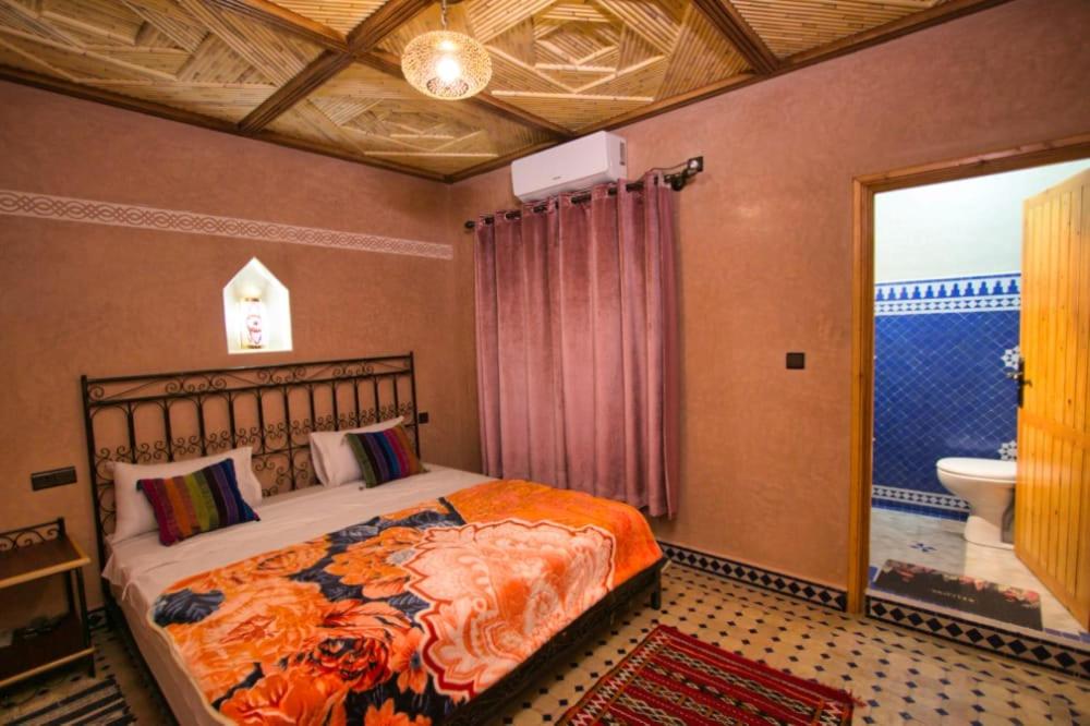 een slaapkamer met een bed en een badkamer met een toilet bij DAR NOUR in Tafraoute