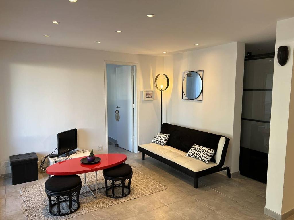 - un salon avec un canapé et une table rouge dans l'établissement APPARTEMENT RENOVE T4 - 6 PERSONNES AVEC PARKING ET JARDIN, au Grau-du-Roi