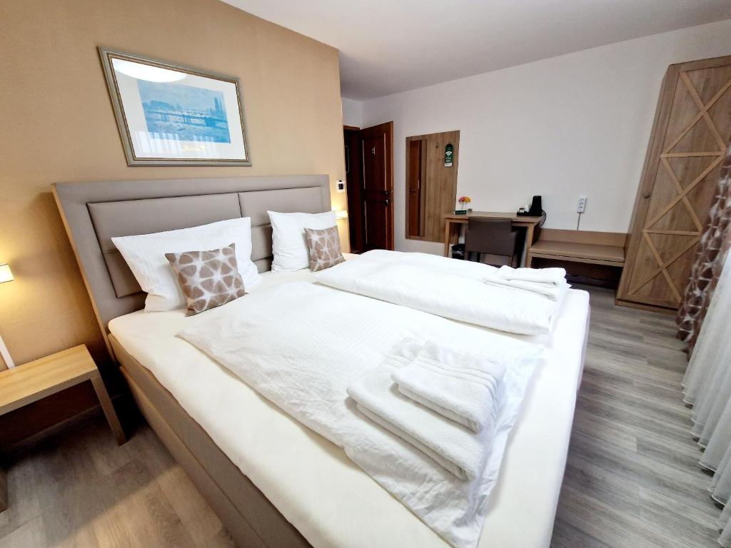 Schlafzimmer mit einem Bett mit weißer Bettwäsche und Kissen in der Unterkunft Hotel Rheintal in Kappel-Grafenhausen