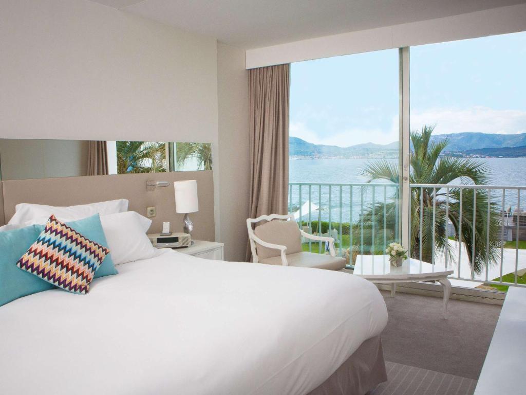 a hotel room with a large bed and a large window at Sofitel Golfe d'Ajaccio Thalassa Sea & Spa in Ajaccio
