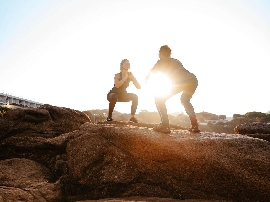 two people standing on some rocks on the rocks at Sofitel Golfe d'Ajaccio Thalassa Sea & Spa in Ajaccio