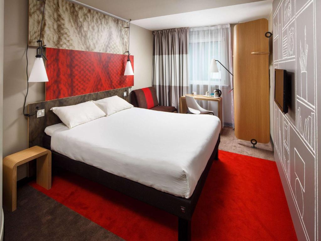 um quarto de hotel com uma cama grande e um tapete vermelho em ibis Glasgow City Centre – Sauchiehall St em Glasgow