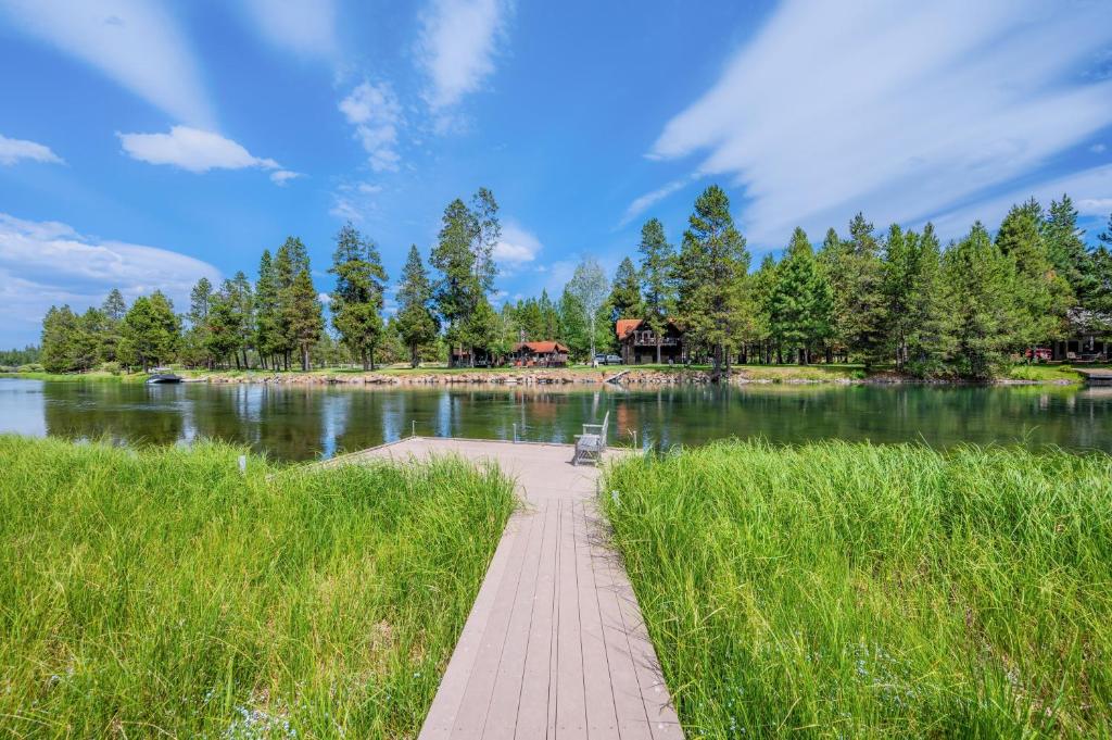 un camino de madera que conduce a un lago con un banco en Riverwatch by AvantStay Deschutes in Your Yard, en Bend