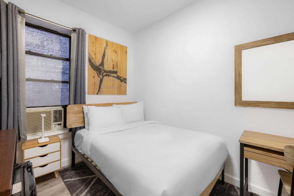 1 dormitorio con cama blanca y ventana en Hotel 27 by LuxUrban en Nueva York