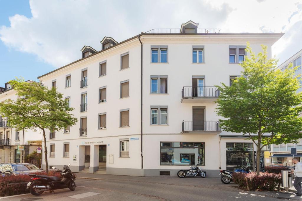 un bâtiment blanc sur le côté d'une rue dans l'établissement VISIONAPARTMENTS Cramerstrasse 8-12 - contactless check-in, à Zurich