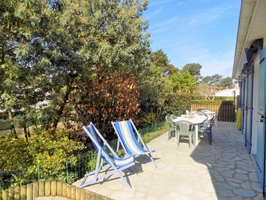 une terrasse avec des chaises bleues, une table et des arbres dans l'établissement La Palmyre - RAVISSANTE MAISON MITOYENNE - proximite CENTRE-VILLE, aux Mathes