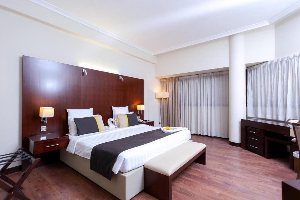 a hotel room with a large bed and a desk at Aavri Hotel in Dubai