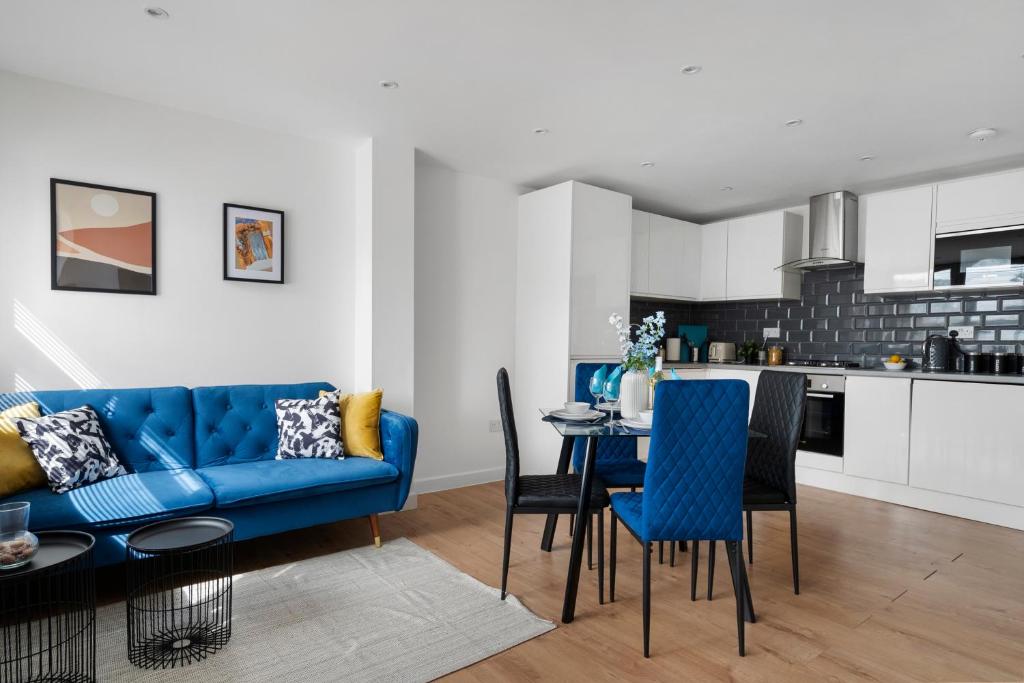 Livestay-Modern Apartments Building in Aylesbury في Buckinghamshire: غرفة معيشة مع أريكة زرقاء وطاولة وكراسي