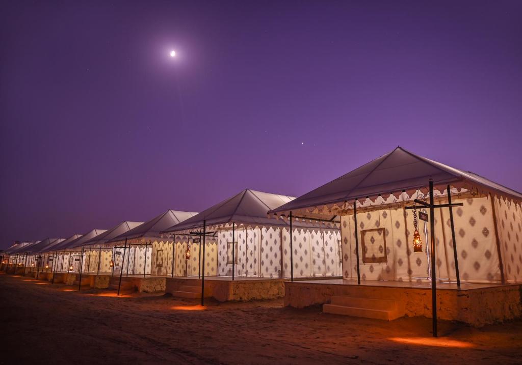 een rij tenten 's nachts met de maan in de lucht bij The Carvaans Resort in Jaisalmer
