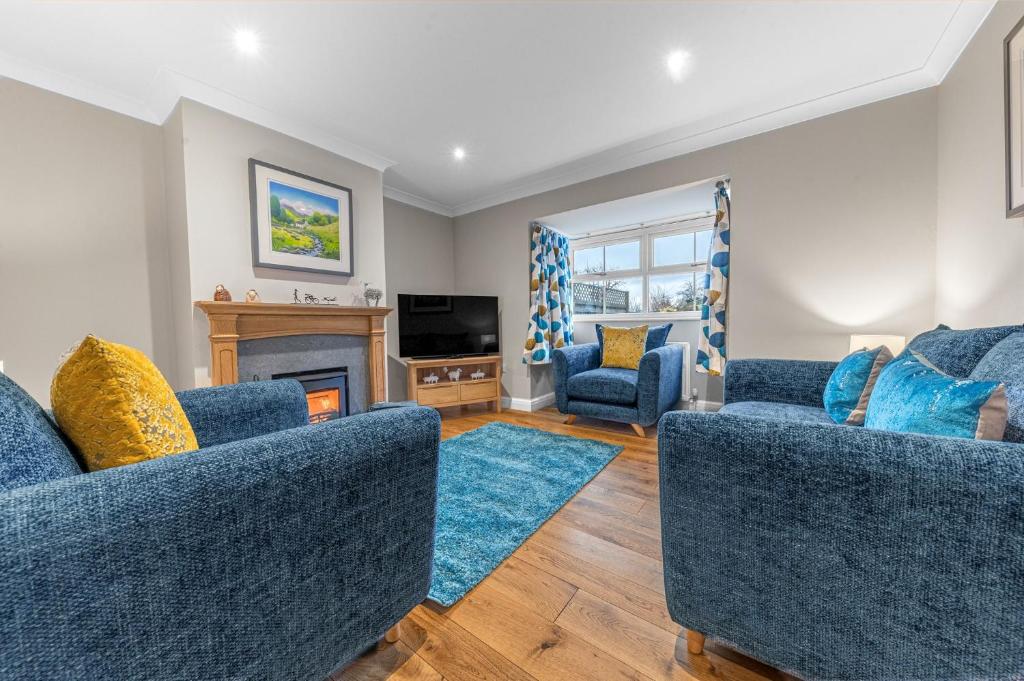 a living room with two blue couches and a fireplace at Summerbank Cottage, luxury Lake District holiday home in Coniston in Coniston